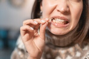 Woman using toothpick to get something out of her teeth.